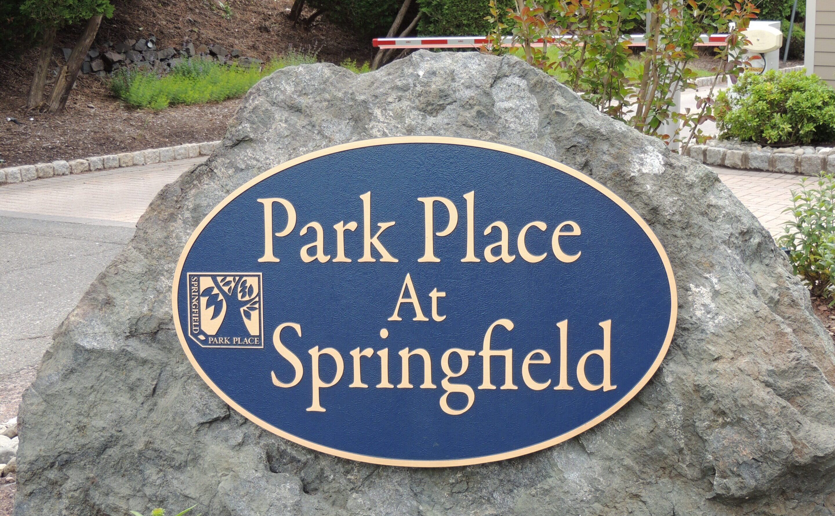 DSCN5270 A large rock with a blue and gold sign reading "Park Place At Springfield" is displayed near a driveway and landscaped area.